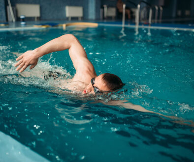 Male swimmer swims on workout in swimming pool